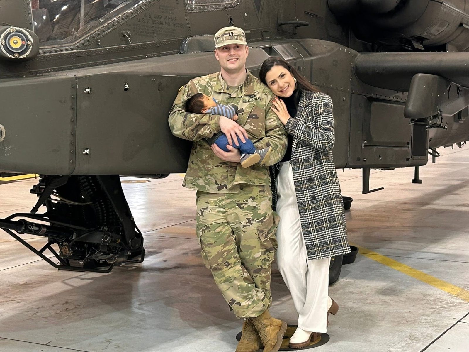 Andrew with his wife and son beside an Apache helicopter